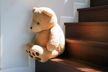 Child concept of sorrow. Teddy bear sitting leaning against the wall of the house alone, look sad...