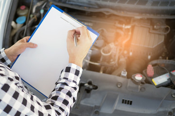 The car mechanic working in the car garage is checking the engine.