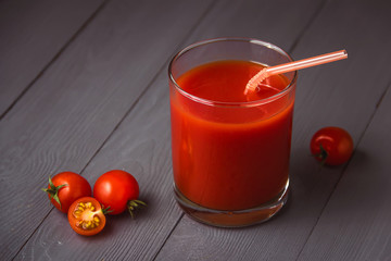 Tomato juice in glasses on gray wooden table.