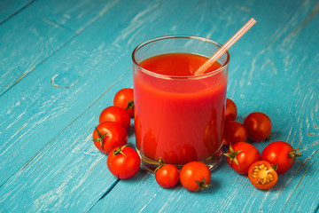 Tomato juice in glasses on blue wooden table.