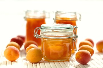 Apricot jam.  jam in glass jars set, fresh ripe apricots on a wooden white table on a light...
