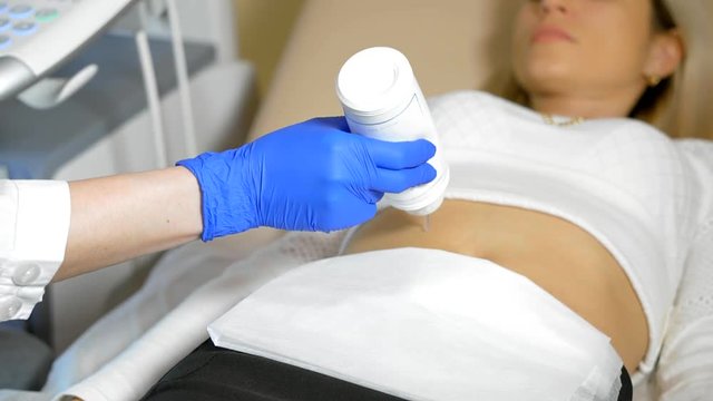 Doctor puts medical gel. A close up the hand of the doctor Taking A Sonogram a stomach the woman