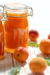 Apricot jam. Orange jam in glass jars set, fresh  apricots on a wooden white table on a light background. High key.Homemade jam.Summer  Canned fruit jam. Healthy vegetarian sweets