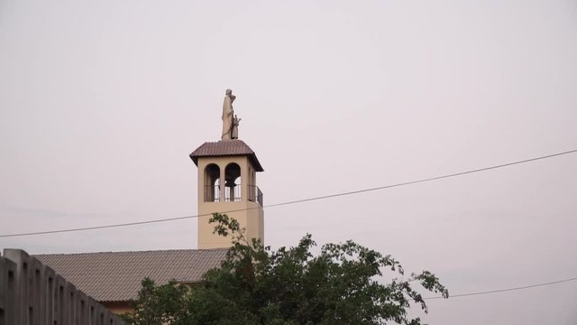 Church steeple and statue during sunset in La Molina, Lima, Peru PANNING FROM RIGHT TO LEFT