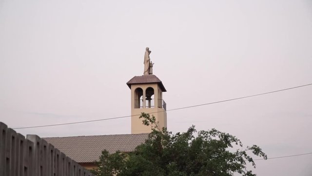 Church steeple and statue during sunset in La Molina, Lima, Peru PAN FROM LEFT TO RIGHT