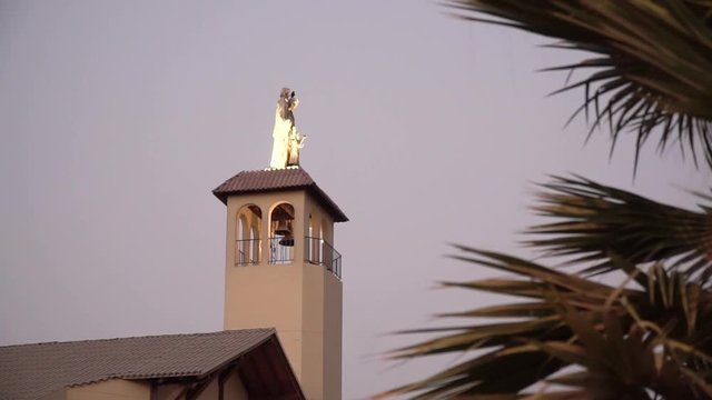 Church steeple and statue illuminated during sunset in La Molina, Lima, Peru