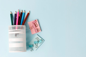 Color pencils in white glass and office on blue background, copy space
