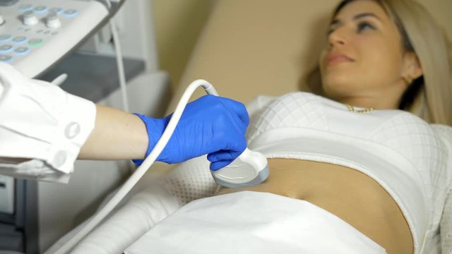 the hand of the doctor Taking A Sonogram a stomach the woman