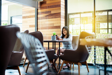 Beautiful asian female using internet with her mobile phone in cafe,Happy and smiling,Positive thinking,Copy space for text