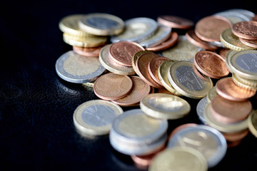 Pile of Euro coins scattered on a dark surface close up