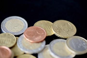 Pile of Euro coins scattered on a dark surface close up