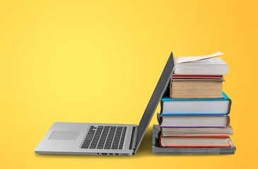 Stack of books with laptop on table