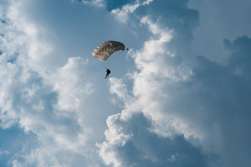 Skydiver with parachute on epic clouds and blue sky background. Copy space