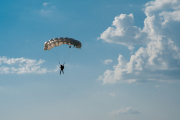 Skydiver with parachute on epic clouds and blue sky background. Copy space