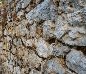 Ancient stone masonry wall overgrown with grass in Greece