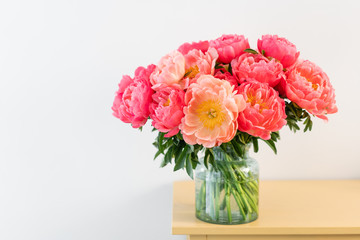 Coral peonies in a glass vase on wooden table.. Beautiful peony flower for catalog or online store. Floral shop concept . Beautiful fresh cut bouquet. Flowers delivery. Copy space