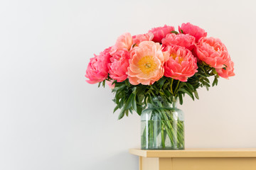 Coral peonies in a glass vase on wooden table.. Beautiful peony flower for catalog or online store. Floral shop concept . Beautiful fresh cut bouquet. Flowers delivery. Copy space