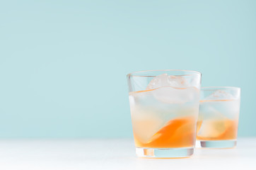 Tropical cool striped alcohol oranges drink with orange liquor, ice cubes, vodka on elegant green color background.