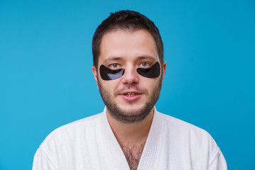 Obraz premium Photo of man with gel pads under eyes and in white robe