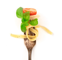 Italian pasta. A closeup of a vintage fork with pappardelle, basil, cheese, tomato, and pepper,...