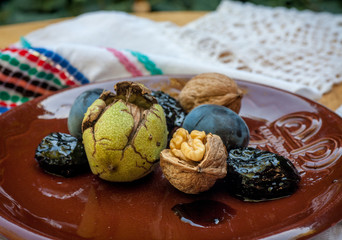 Fresh and dried prunes on plate.