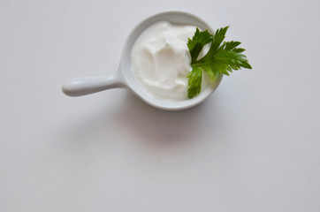 white sauce in a saucepan with greens, parsley, cilantro on a white background