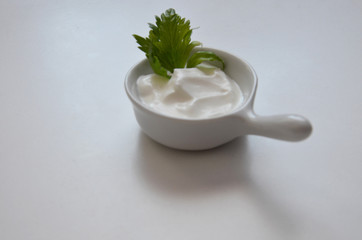 white sauce in a saucepan with greens, parsley, cilantro on a white background