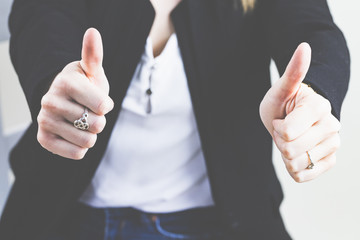Fröhliche junge Frau hat die Daumen hoch - sie freut sich über Ihren Erfolg. 