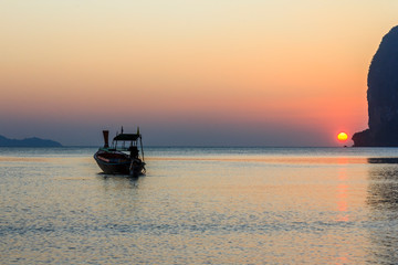Fototapeta na wymiar Long Tail boat moored off Pak Meng beach, Trang Province, Thailand as the sun is about to set over the horizon.