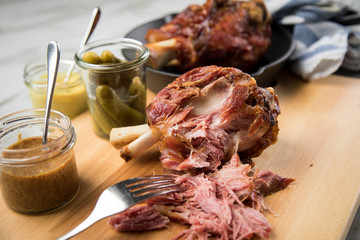Gegrilltes Schweinefleisch Haxen Fleisch auf Holzbrett mit Cornichons, süßen und mittelscharfen Senf auf Marmor Hintergrund