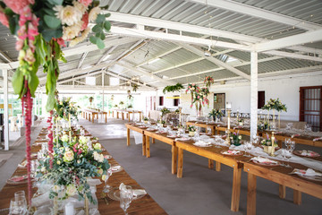 Decorations, hanging flower bouquet, wooden tables and table settings at a wedding reception
