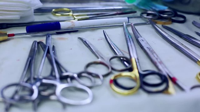Concept medicine, surgery. Operating table with a tool for surgery, closeup, blue light. On the table are spread out the sterilny instruments of surgeons, scalpels, clips, tampons, syringes.