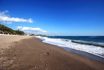 Fototapeta na wymiar View along a quiet Daitona beach and coastline, Marbella, Spain.