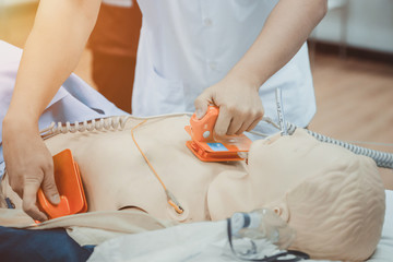 hands of doctor holding defibrillator electrods, performing defibrillation or electropulse therap - obrazy, fototapety, plakaty