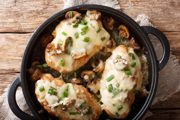Baked chicken breast with mushrooms, green onions, mozzarella and parmesan close-up in a pan. Horizontal top view