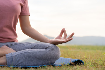 Fototapeta na wymiar close up hand and half body of health woman sit in lotus yoga position in the morning at park. Practicing yoga makes meditation for healthy breathing and relaxation