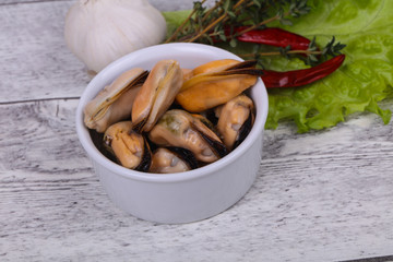 Pickled mussels in the bowl served pepper, garlic and salad