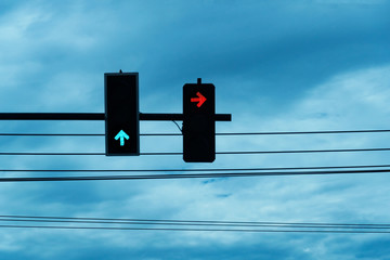 red and green arrow with transport traffic light on black electric wire on blue sky background