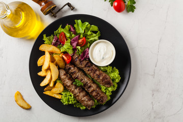 Traditional cevapcici served with baked potatoes. Flat lay. Stone background.