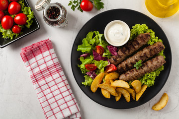 Traditional cevapcici served with baked potatoes. Flat lay. Stone background.