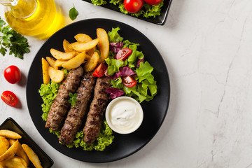 Traditional cevapcici served with baked potatoes. Flat lay. Stone background.
