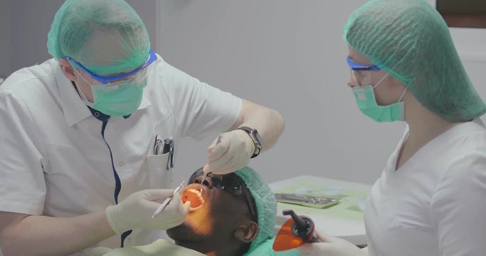 Dentist and assistant do ultraviolet filling
