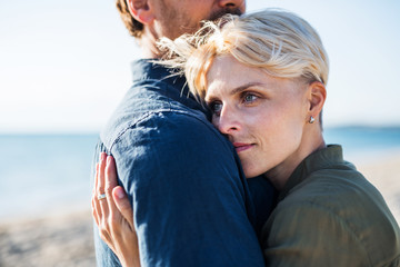 Midsection of young couple standing outdoors on beach, hugging. Copy space.