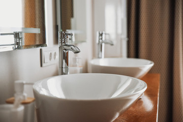 Modern stylish washbasins with chrome taps. Luxury lifestyle. Close-up, selective focus Wood texture