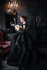 Attractive woman in black dress in medieval interior