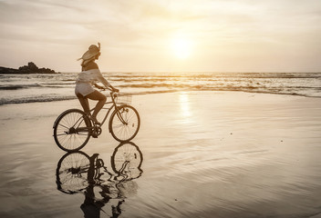 Fototapeta na wymiar Happiness woman traveler with her bicycle rides on sea coastline