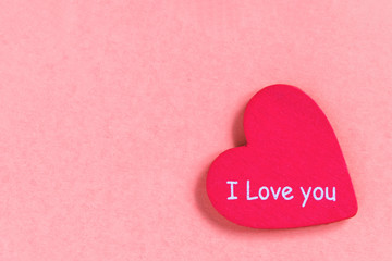 Pink heart with text love you on pink background.