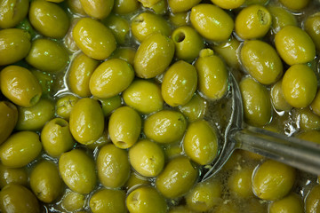 Fresh green homemade olives in oil barrel