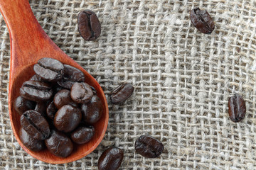 Coffee beans in wooden spoon. Close up macro photography.