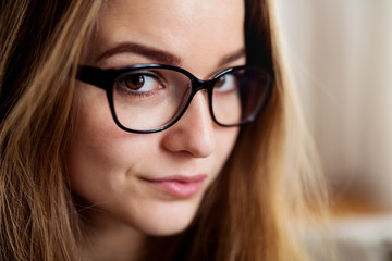A close-up portrait of young female student standing indoors.
